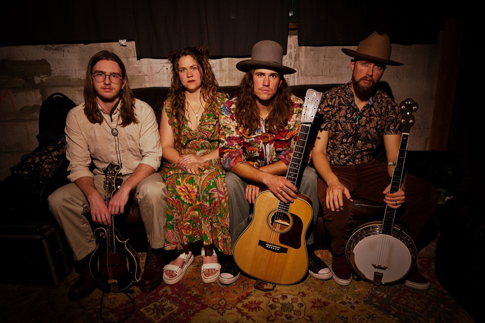 Remedy Tree — the four members seated against a whitewashed brick wall, with guitar and banjo